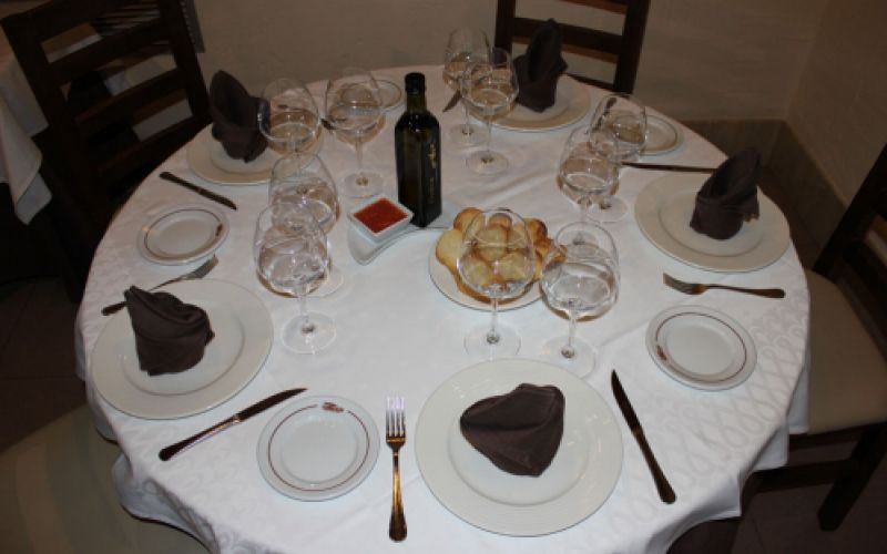 Mesa y sillas preparadas en comedor con pan y vino para varios comensales  de Restaurante Venta San José en Zafra de Záncara