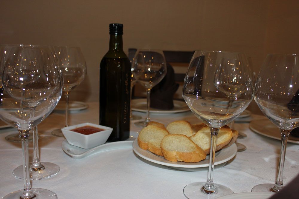 Mesa preparada en salón comedor con pan y vino para varios comensales  de Restaurante Venta San José en Zafra de Záncara