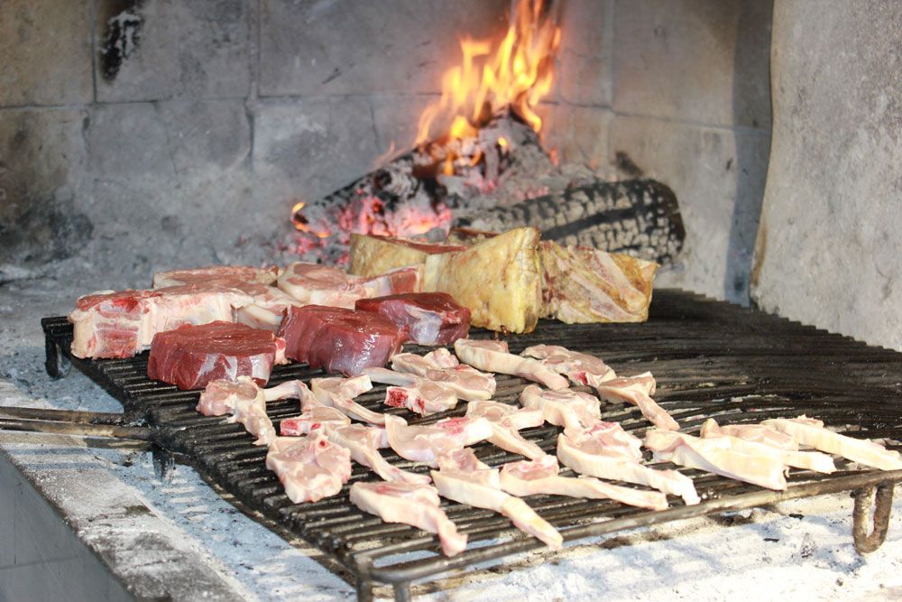 Parrilla encendida con varios tipos de carnes en Restaurante Venta San José en Zafra de Záncara