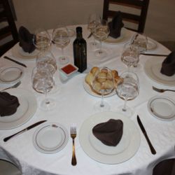 Mesa y sillas preparadas en comedor con pan y vino para varios comensales  de Restaurante Venta San José en Zafra de Záncara