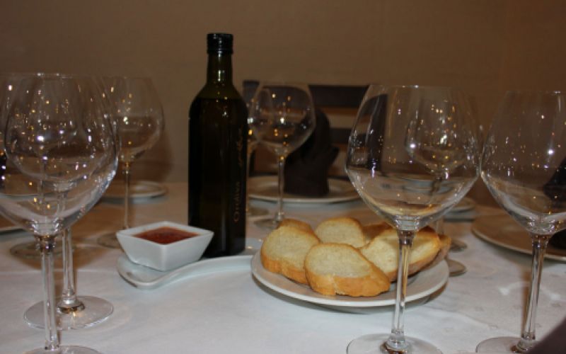 Mesa preparada en salón comedor con pan y vino para varios comensales  de Restaurante Venta San José en Zafra de Záncara