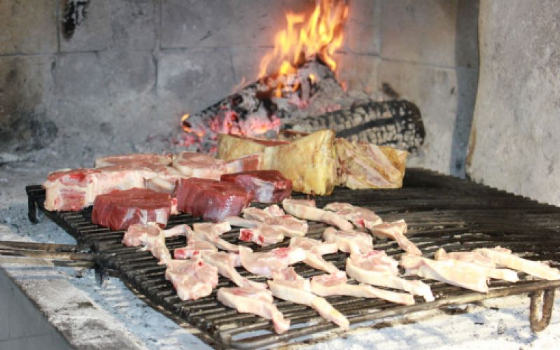 Parrilla encendida con varios tipos de carnes en Restaurante Venta San José en Zafra de Záncara