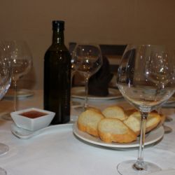 Mesa preparada en salón comedor con pan y vino para varios comensales  de Restaurante Venta San José en Zafra de Záncara